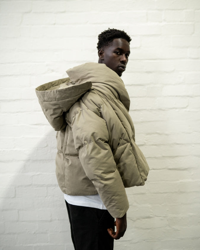 Hooded khaki puffer jacket worn by male model side veiw