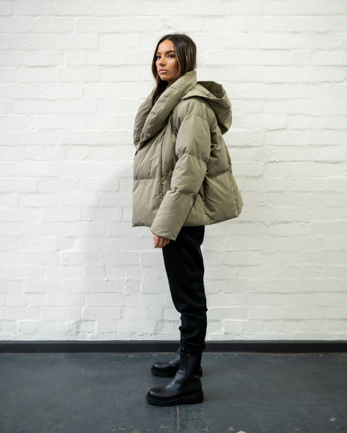 Khaki puffer jacket worn by female model full body side view