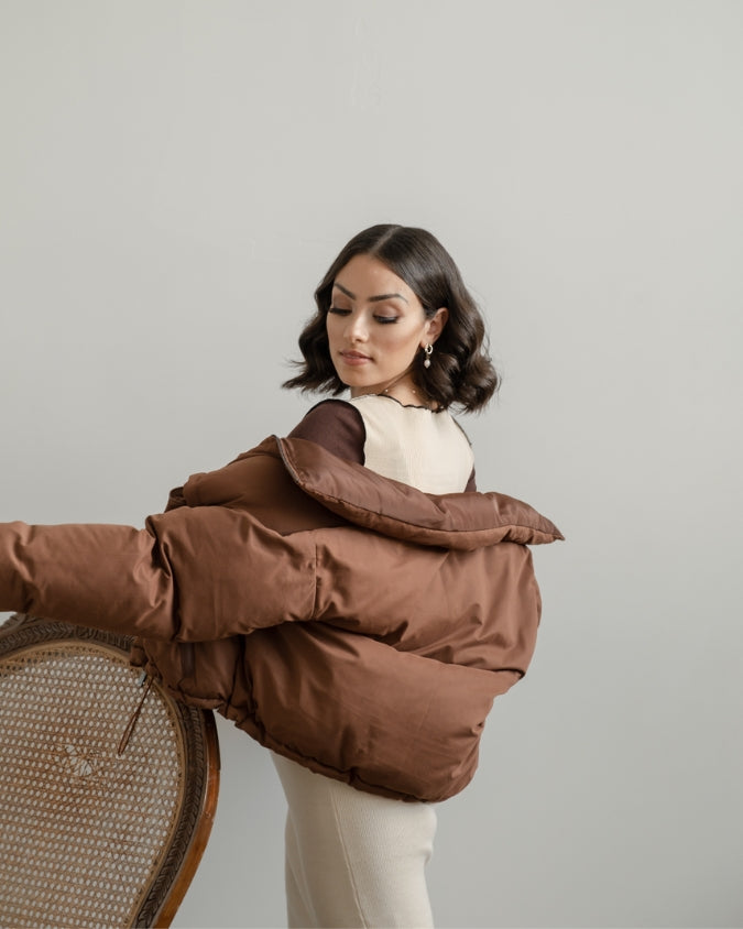 Close up of Chocolate brown cropped puffer jacket worn by female model with dress