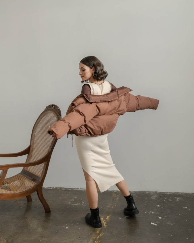 Chocolate cropped puffer jacket worn by female model with dress indoors