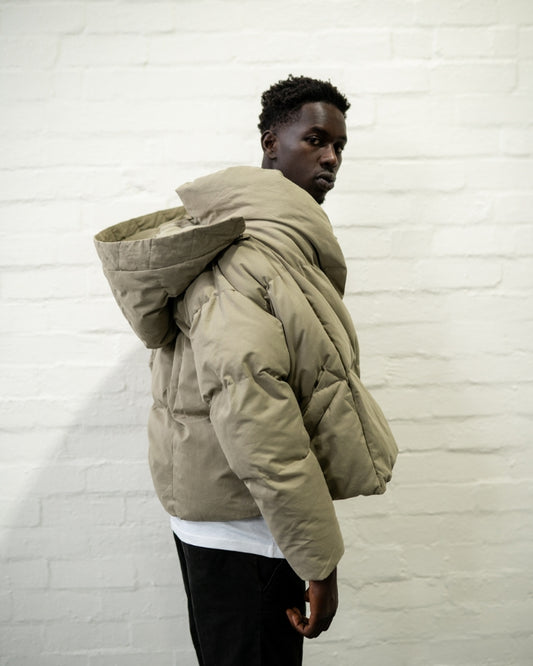Hooded khaki puffer jacket worn by male model side veiw