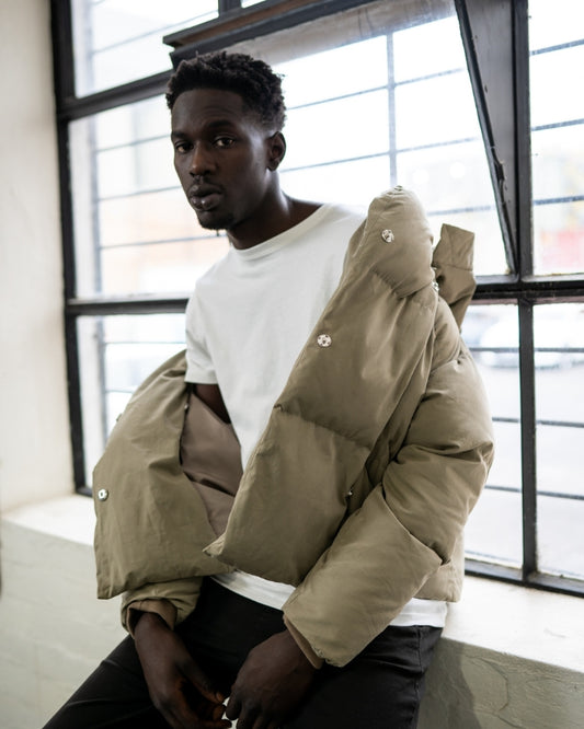 Khaki puffer jacket worn off-shoulder by male model