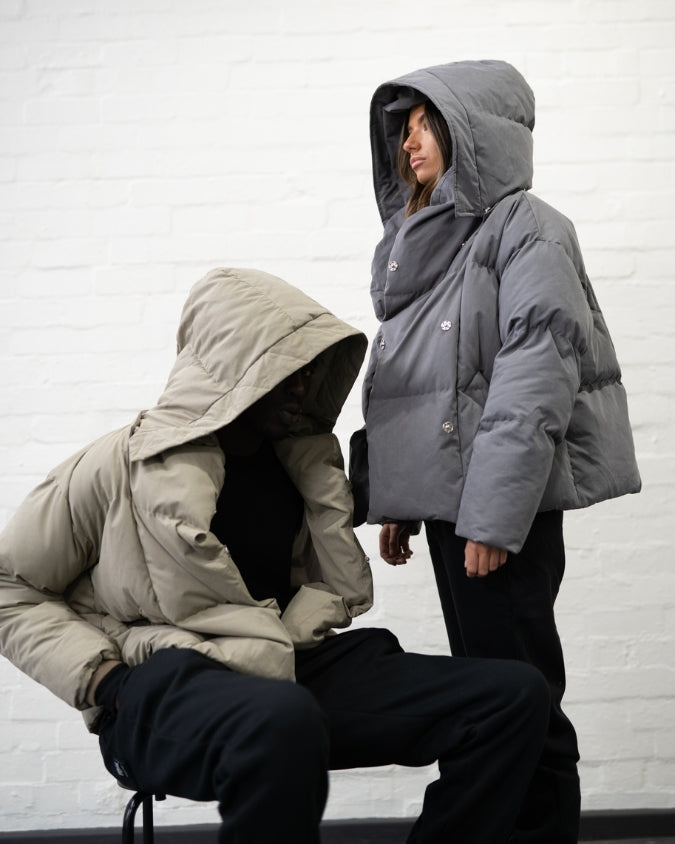 Khaki puffer jacket worn by male model and Charcoal puffer jacket worn by female model