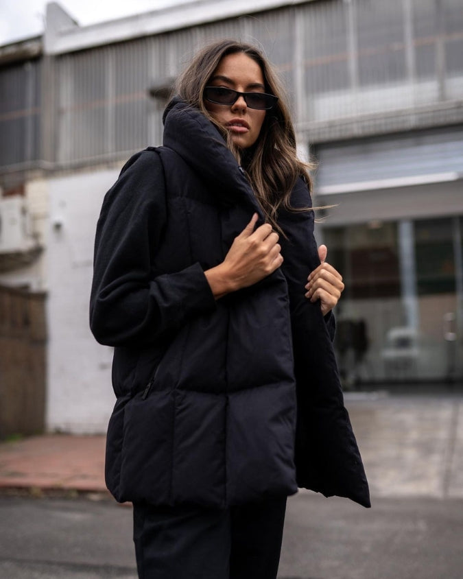 Womens black longline puffer vest worn by female model outdoors